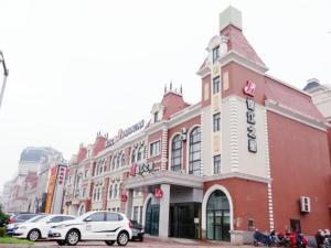 a building on a street with cars parked in front of it at Jinjiang Inn Jinzhou Yunfei Bridge in Jinzhou