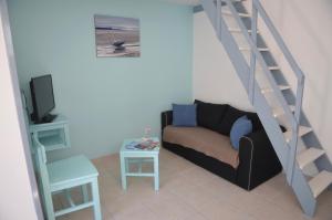 a living room with a couch and a staircase at Maisonnette Gatseau in Saint-Trojan-les-Bains