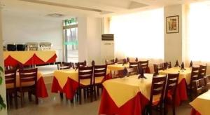 Un restaurante con mesas y sillas con mantel rojo y amarillo. en GreenTree Inn Tangshan Yuhua Road, en Fujiatun