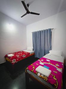 a bedroom with two beds and a ceiling fan at Murdeshwar Savion Homestay in Māvalli