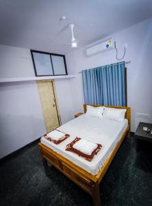 a bedroom with a bed with white sheets and pillows at Murdeshwar Savion Homestay in Māvalli