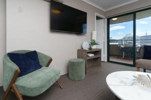 un salon avec une chaise et une télévision dans l'établissement Central 2BR apartment, Hotel vibe, Walk everywhere - Hosted by Canstay, à Braddon