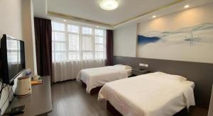 a hotel room with two beds and a flat screen tv at GreenTree Inn HanZhong Railway Station Beiyihuan Road Express Hotel in Shima