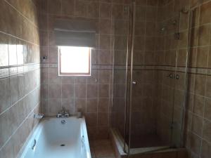 a bathroom with a shower and a bath tub at Royal Thokazi Lodge in Nongoma