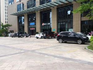 un estacionamiento con autos estacionados frente a un edificio en Jinjiang Inn Select Jiaxing Wanda Plaza en Jiaxing