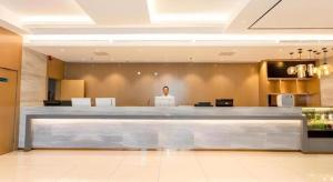 a person standing in a lobby with a large counter at City Comfort Inn Beiliu Bus Terminal in Beiliu