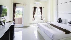 a white bedroom with two beds and a table at The Rich Residence in Ban Tha Kup +40 photos