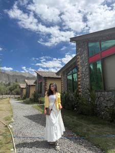 a woman in a white dress standing in front of a house at LOKAL Rooms x Skardu (Katpana Retreat) in Skardu