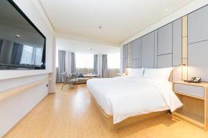 JI Hotel Shanghai North Hi-Tech Industrial Park في شانغهاي: غرفة نوم بها سرير كبير وتلفزيون بشاشة مسطحة