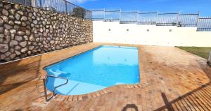 a swimming pool on a patio with a stone wall at Sunset Heights 23 Coastal Sanctuary in Langebaan