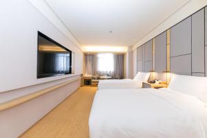 JI Hotel Shanghai North Hi-Tech Industrial Park في شانغهاي: غرفة فندق بها سريران وتلفزيون بشاشة مسطحة