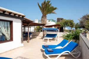 a patio with blue lounge chairs and a palm tree at Villa Sol in Charco del Palo