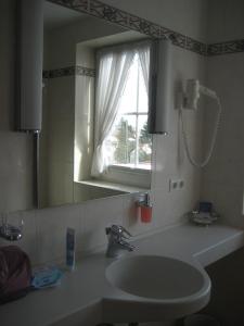 baño con lavabo, espejo y ventana en Hotel-Gasthof Maisberger, en Neufahrn bei Freising