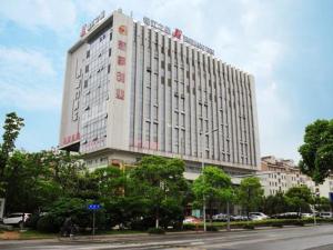 a large white building with a person riding a bike in front of it at Jinjiang Inn Suzhou Wuzhong Wanda Plaza Canglang New Estate in Suzhou