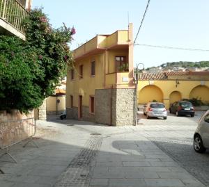 a street with cars parked in front of a building at La Casa Rosada Arbus in Arbus