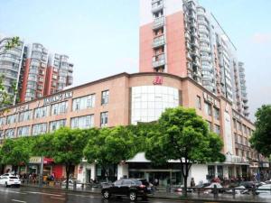 - un grand bâtiment en briques dans une rue de la ville avec des voitures dans l'établissement Jinjiang Inn Wujiang Zhongshan North Road, à Suzhou