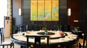 a round table with chairs and a painting on the wall at Zhuhai Golden Gulf Golf Glub in Huang-lü-pei