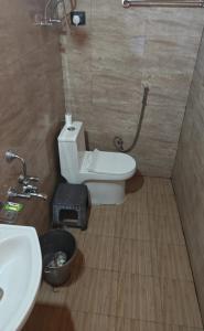 a bathroom with a white toilet and a sink at Buransh Retreat in Jageshwar