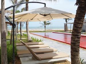 a group of lounge chairs under an umbrella next to a pool at Red Z The Ocean in Ban Tanot Noi