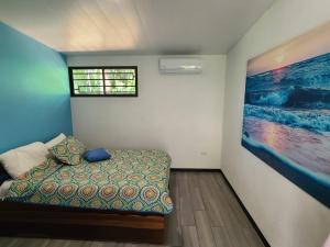 a bedroom with a bed and a painting on the wall at Pura Vida - Villa Elenita in Parrita +40 photos