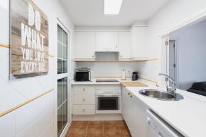 a kitchen with white cabinets and a sink at Vista Marina de Isla Canela in Isla del Moral