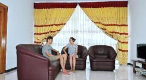 two people sitting on a couch in a living room at Hotel Glee in Challi
