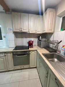 a kitchen with white cabinets and a stove and a sink at Guest House Robin Hud in Cherni Osŭm