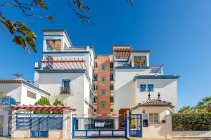 a tall white building with a blue gate at Vista Marina de Isla Canela in Isla del Moral
