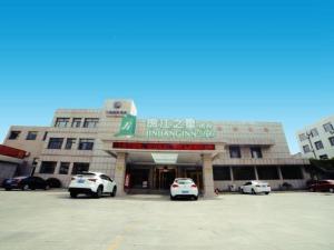 two cars parked in a parking lot in front of a building at Jinjiang Inn Select Yantai Penglaige in Penglai