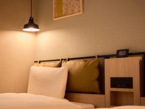 una camera da letto con letto, cuscini e lampada di Comfort Hotel Mito a Mito
