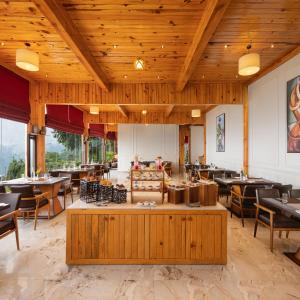 a restaurant with wooden ceilings and wooden tables and chairs at WelcomHeritage Arka Resort & Spa, Rishikesh in Bijni