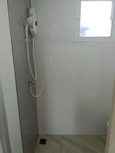 Una ducha en un baño blanco con ventana. en Comfy Hotels Suvarnabhumi Airport, en Samut Prakan