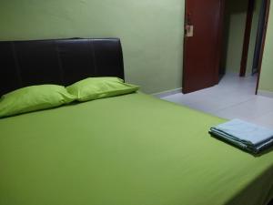 a green bed with a black headboard and a green blanket at Homestay pantai dungun in Dungun