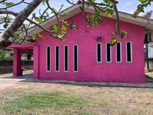 a pink house with black shuttered windows at Homestay pantai dungun in Dungun
