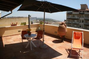 a patio with a table and an umbrella on a balcony at Valverde Penthouse in Sciacca