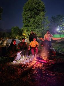 un grupo de personas sentadas alrededor de un fuego en Safarnama Hornbill Camping near festival ground, en Jāmb