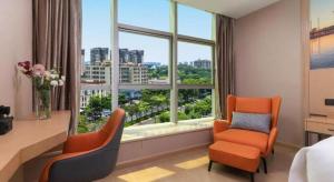 ein Hotelzimmer mit einem Schreibtisch und Stühlen sowie einem großen Fenster in der Unterkunft Vienna Hotel Shenzhen International Exhibition Center Fuhai Qiaotou in Fenghuangwei
