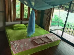 a bedroom with a bed with a canopy and a balcony at The Big House in Koh Chang Ranong