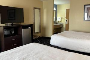 a hotel room with two beds and a flat screen tv at Baymont by Wyndham Evansville North/Haubstadt in Haubstadt +28 photos