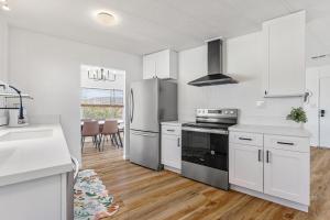 Una cocina con gabinetes blancos y un refrigerador de acero inoxidable. en Desert Winds SkyHouse Mountain View Retreat, en Desert Hot Springs