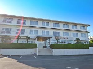 a large white building with palm trees in a parking lot at Anori Seaside Hotel in Ōsasu