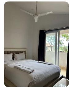 a white bedroom with a bed and a window at Vista Vagator Junction by Dia Hotels and Homes in Anjuna
