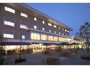 Un edificio con mesas y sombrillas delante. en Hotel Ligare Kasugano, en Nara