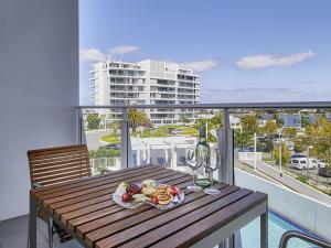 a table with a plate of food and wine glasses on a balcony at The Sebel Mandurah in Mandurah