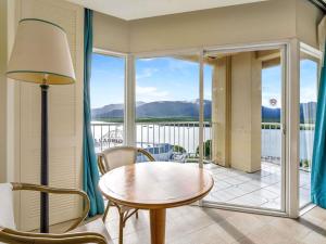 a living room with a table and chairs and a balcony at Pullman Cairns International in Cairns