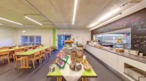 a restaurant with a counter with tables and chairs at DJH Jugendherberge Chemnitz "eins" in Chemnitz