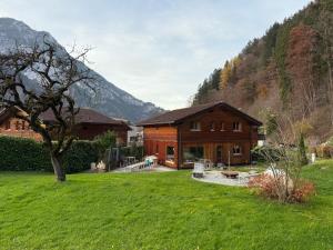 a wooden house in the mountains with a green yard at Chalet Auszeit Montafon in Bartholomäberg