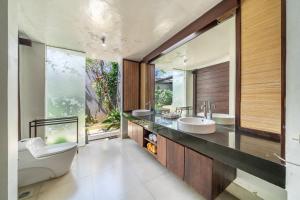 a bathroom with two sinks and a large window at Villa Sage Bali in Darmasaba +27 photos