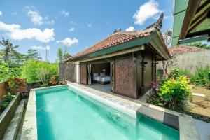 a villa with a swimming pool and a house at Villa Sage Bali in Darmasaba