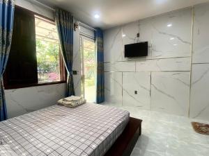 une chambre avec un lit et une télévision sur un mur dans l'établissement Nhà Nghỉ THẢO NGUYÊN XANH, à Buôn Ma Thuột
